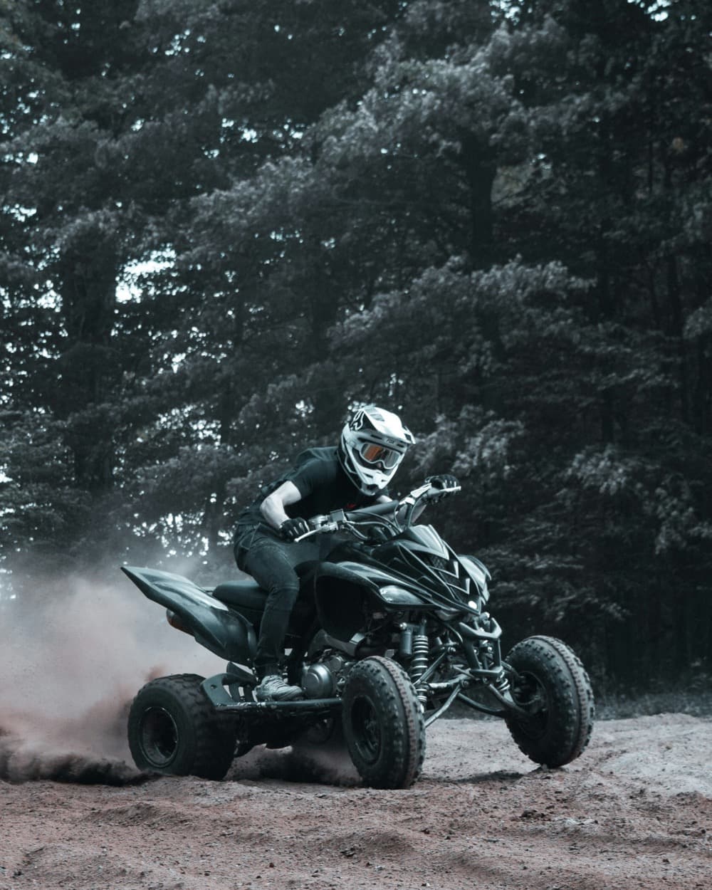 A quad-bike rider kicking up dust on a forest trail